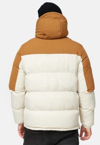 Puffy jacket with a brown upper section and cream lower section. Features a hood, horizontal quilted design, and elastic cuffs.
