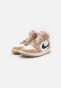 Beige a bílé vysoké tenisky s černým logem Nike Swoosh, obsahující perforovanou špičku, ploché tkaničky a texturovanou gumovou podrážku.