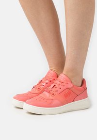 Rosa lädersneakers med vita gummisulor, perforerat tårområde och märkesdetaljer på sidorna. Snörningsdesign med vadderade kragar.