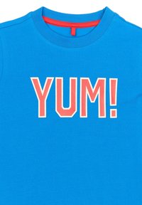 Modré tričko s kulatým výstřihem, s nápisem "YUM!" v tučných růžových písmenech. Materiál se zdá být měkký a má hladkou texturu.