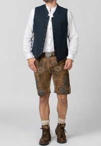 Blaues Wollwesten mit silbernen Knöpfen, kombiniert mit braunen Lederhosen mit blauer Blumenstickerei, cremefarbenen Socken und braunen Stiefeln.