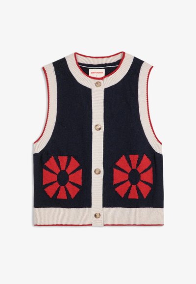 Granatowy dzianinowy bezrękawnik z białymi wykończeniami, czerwonymi okrągłymi wzorami z przodu i trzema brązowymi guzikami pośrodku.