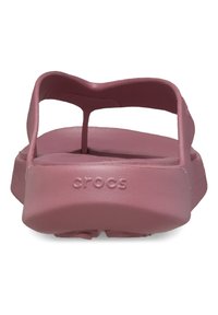 Zuecos rosa con un acabado mate y suave, que cuentan con una correa trasera y un diseño minimalista. El logotipo de la marca está grabado en el talón.