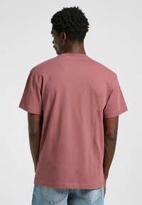 Mörkröd bomullströja med korta ärmar, rund halsringning och avslappnad passform. Slät textur och minimala sömnadsdetaljer vid fållen.