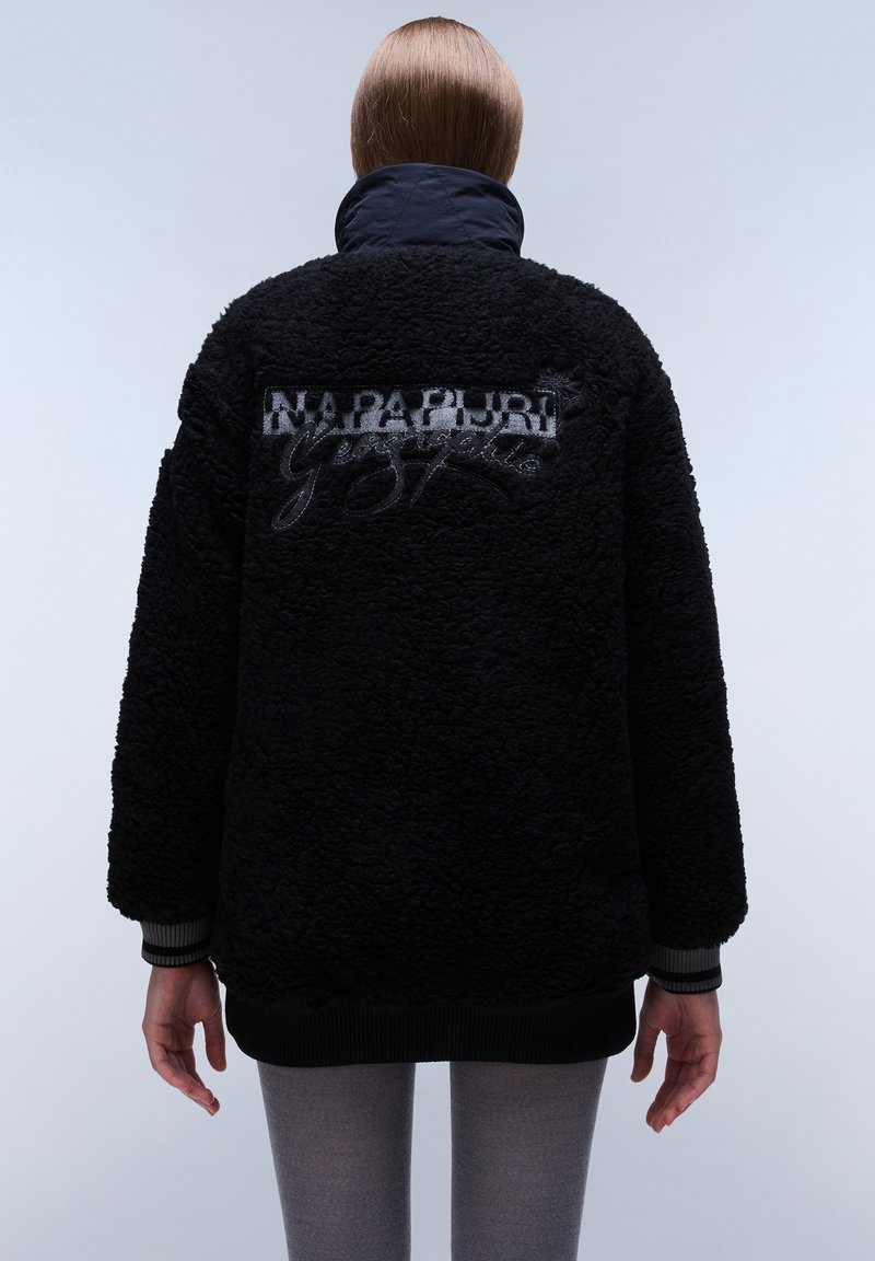 Veste en polaire noire avec col matelassé, poignets et ourlet côtelés. Logo brodé "Napapijri" au dos. Surface douce et texturée.