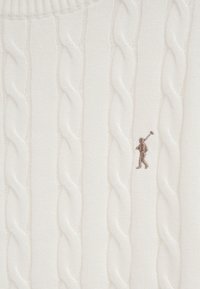 Tissu blanc en maille torsadée avec une petite figure brodée représentant une personne portant un maillet en fil marron.