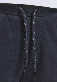 Marine joggebukser med tekstur, som har svarte øyer og flettede snorer med kontrasterende hvite flekker.