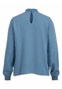 Modrý bluzon s dlouhým rukávem a nařaseným výstřihem a manžetami, který má detail v podobě klíčové dírky na zádech a hladkou, mírně lesklou tkaninu.