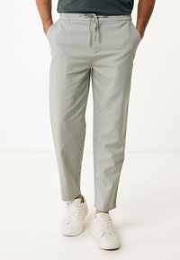 Lichtgrijze, taps toelopende broek met een elastische tailleband en een trekkoord. Bevat zijzakken en een glad, gestructureerd weefsel.