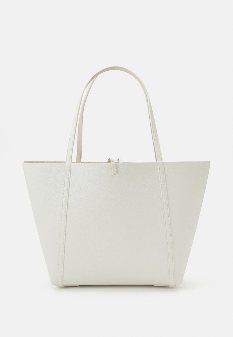 Sac fourre-tout blanc texturé avec deux longues anses, une forme triangulaire, présentant un design minimaliste et une petite fermeture centrale.