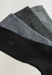 Trei perechi de șosete cu striații în negru, gri închis și gri deschis. Fiecare are un logo subtil brodat aproape de botișor. Material moale, texturat.