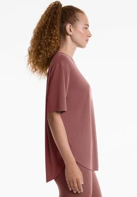 Top a maniche corte e vestibilità comoda in rosa polveroso, realizzato in tessuto morbido, con orlo arrotondato e design semplice senza motivi o accenti.
