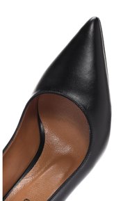 Zapato de tacón de punta afilada en cuero negro con textura suave y un interior color canela, que presenta un corte alto a lo largo de los laterales y sin herrajes visibles.