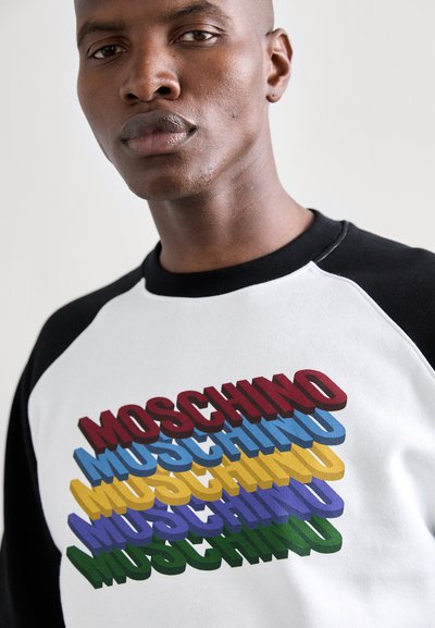 Biała bluza z czarnymi rękawami raglanowymi z wielokolorowym tekstem 3D "MOSCHINO" w kolorach czerwonym, niebieskim, żółtym, zielonym i fioletowym. Gładka bawełniana tekstura.