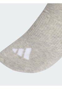 Siva čarapa s mekim, teksturiranim pletenjem i bijelim detaljem s tri pruge na vrhu prstiju. Zaobljeni dizajn vrha prsta.