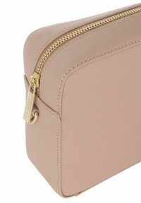 Beżowa kosmetyczka o fakturowanej powierzchni z złotym zamkiem błyskawicznym. Posiada prostokątny kształt i małą pętlę z boku do zawieszenia. Prosty design.