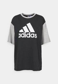 Černé a šedé krátké tričko s krátkými rukávy vyrobené z bavlny, s velkým bílým logem Adidas na přední straně a kulatým výstřihem.