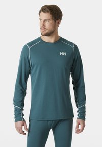 Langarm teal thermoshirt in een textuurstof met grijze accenten en logo op de borst, met een strakke pasvorm en een ronde hals.