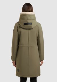 Oliven grøn parka med hætte foret med kunstpels, quiltede detaljer og et logo-patch på venstre side, der har en lige silhuet og lange ærmer.