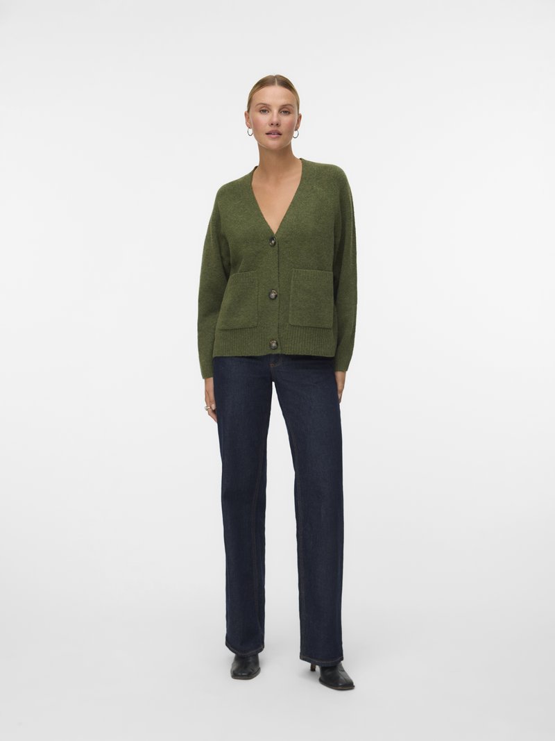 Cardigan verde-azeitona com decote em V, três botões e dois bolsos frontais. Ajuste casual, textura suave e punhos canelados, combinado com jeans escuros.