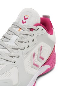 Hvid atletiksko med rosa accenter, tekstureret stof og kontrasterende sål. Indeholder snørebånd og logo på tungen. Siden viser et designmønster.