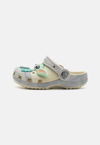 Clog featuring a beige body, gray accents, and molded character details. Made of durable material with ventilation holes and a heel strap.