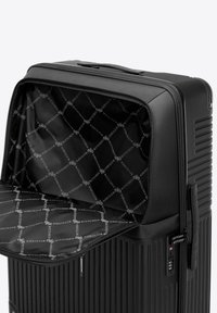 Valise rigide noire avec un extérieur rainuré, fermeture éclair, poignée de transport et intérieur en tissu à motif comportant le nom de la marque.