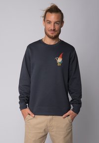 Sweatshirt bleu marine à manches longues, col rond, avec un graphisme de gnome sur le côté gauche de la poitrine. Matériau en mélange de coton avec des poignets côtelés.