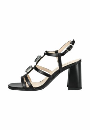 Sandale noire à talon haut avec talon carré, bride de cheville avec boucle, trois fines brides sur les orteils, et deux grandes décorations en cristal carré.