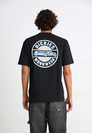 Black cotton t-shirt with a circular blue and cream graphic on the back, featuring text "DICKIES WORKWEAR" and a vintage truck illustration.