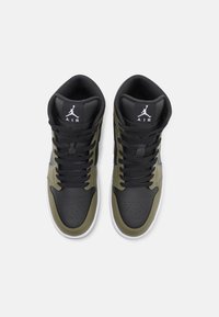 High-top basketball sneakers made of black leather with olive-green accents, featuring perforated toe, black laces, and a white logo.