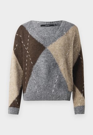 Langermet V-hals genser med geometrisk lappeteknikk i grått, brunt og beige, med stikkede detaljer på en ensfarget bakgrunn.