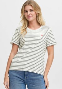 T-shirt à manches courtes couleur crème avec des rayures noires et un petit motif de cœur rouge sur le côté gauche de la poitrine. Fabriqué en coton doux.
