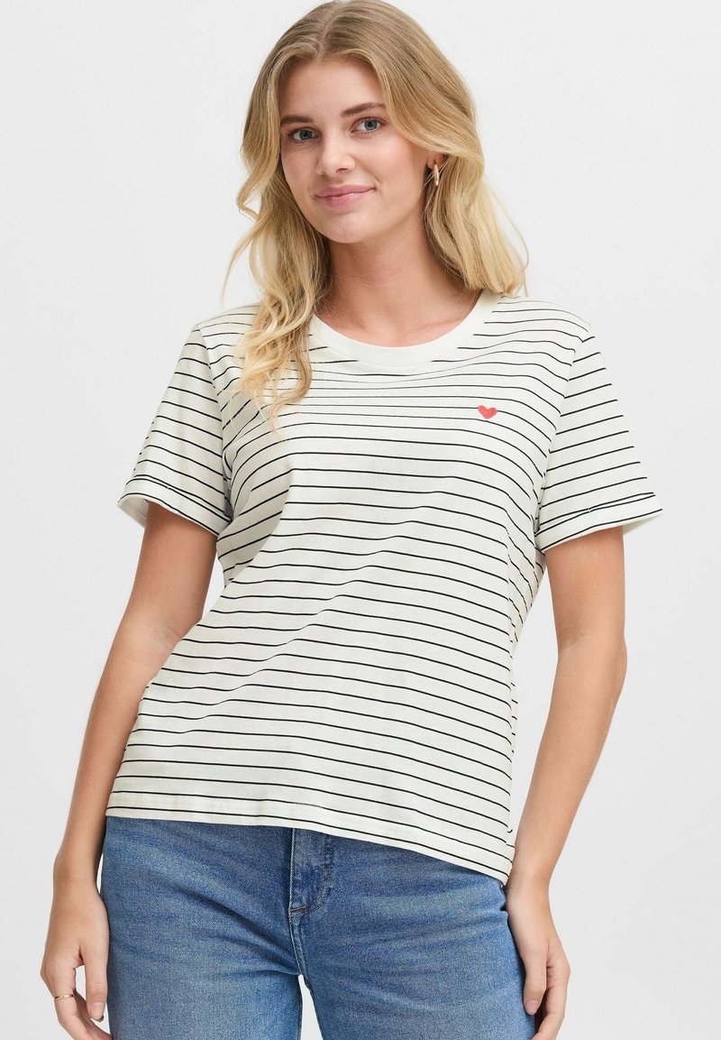 T-shirt à manches courtes couleur crème avec des rayures noires et un petit motif de cœur rouge sur le côté gauche de la poitrine. Fabriqué en coton doux.