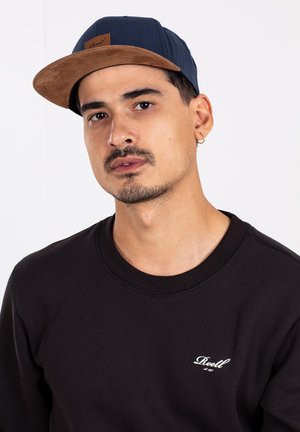 Black sweatshirt with a round neck and embossed logo, paired with a navy cap featuring a brown suede brim and logo patch.