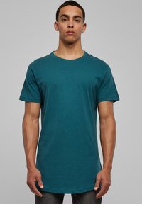 Tricou turcoaz cu guler rotund, confecționat dintr-un material moale, având mâneci scurte și o tivă dreaptă. Textură netedă, fără modele sau accente vizibile.