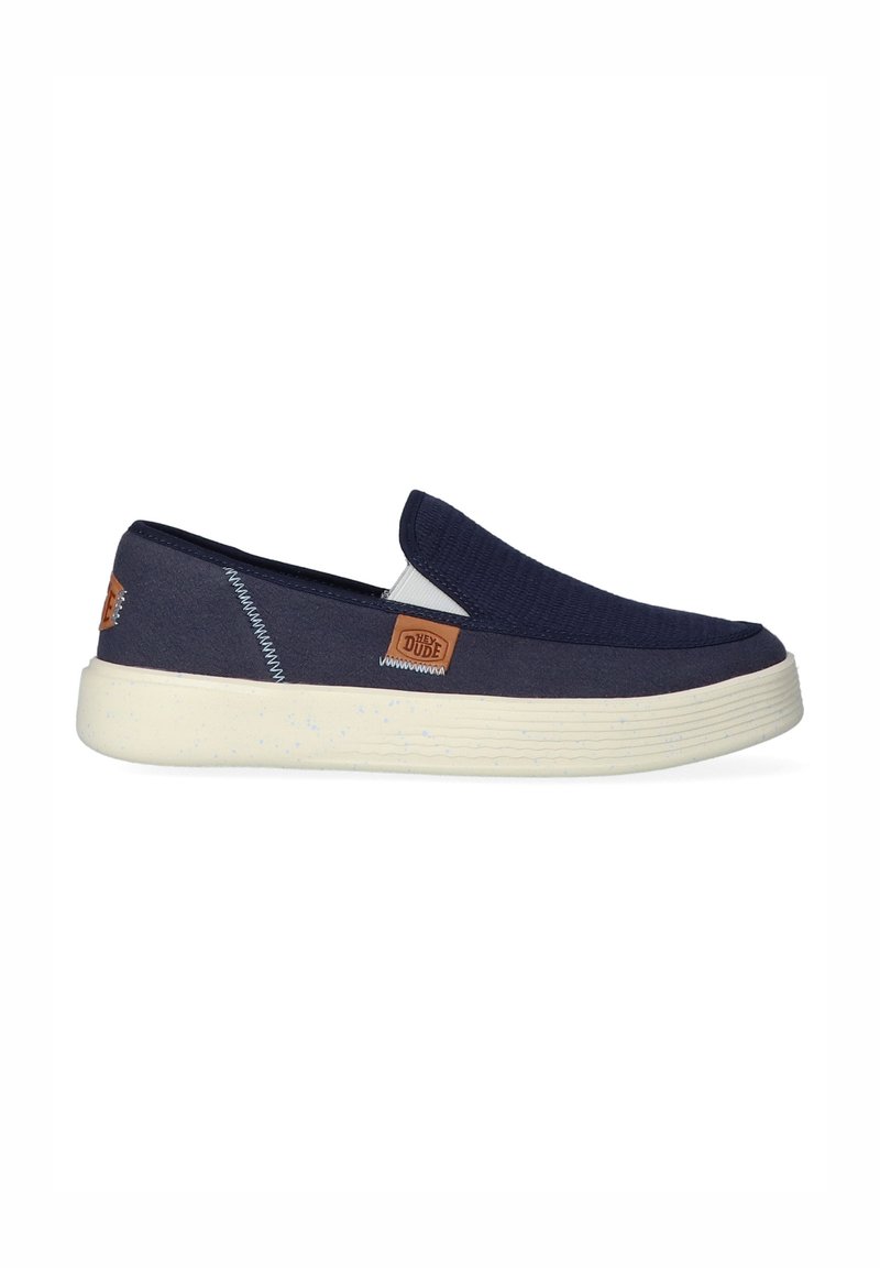 Marine slip-on schoenen met een gestructureerde bovenkant, een licht gevlekte zool en tan logo-accenten aan de zijkant. Eenvoudig, casual ontwerp.