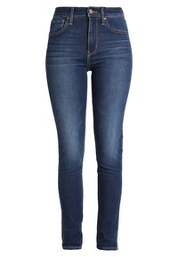 Jeans ajustados de mezclilla azul oscura con talle alto, material de mezclilla, decoloración sutil, diseño clásico de cinco bolsillos y cierre con botón metálico.