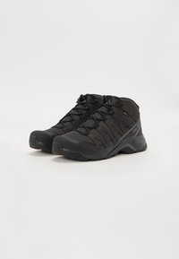 Czarne buty trekkingowe wykonane z siateczki i materiałów syntetycznych, w stylu średnio-krocznym, z gumową podeszwą i wzmocnionym noskiem dla większej trwałości.
