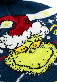 Beanie a maglia con un personaggio Grinch verde dagli occhi gialli, berretto di Babbo Natale rosso e sfondo blu navy; include fiocchi di neve bianchi e dettagli.