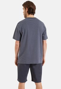 T-shirt gris rayé avec des lignes bleu clair, à manches courtes et col rond, associé à un short foncé. Tissu en mélange de coton, coupe décontractée.
