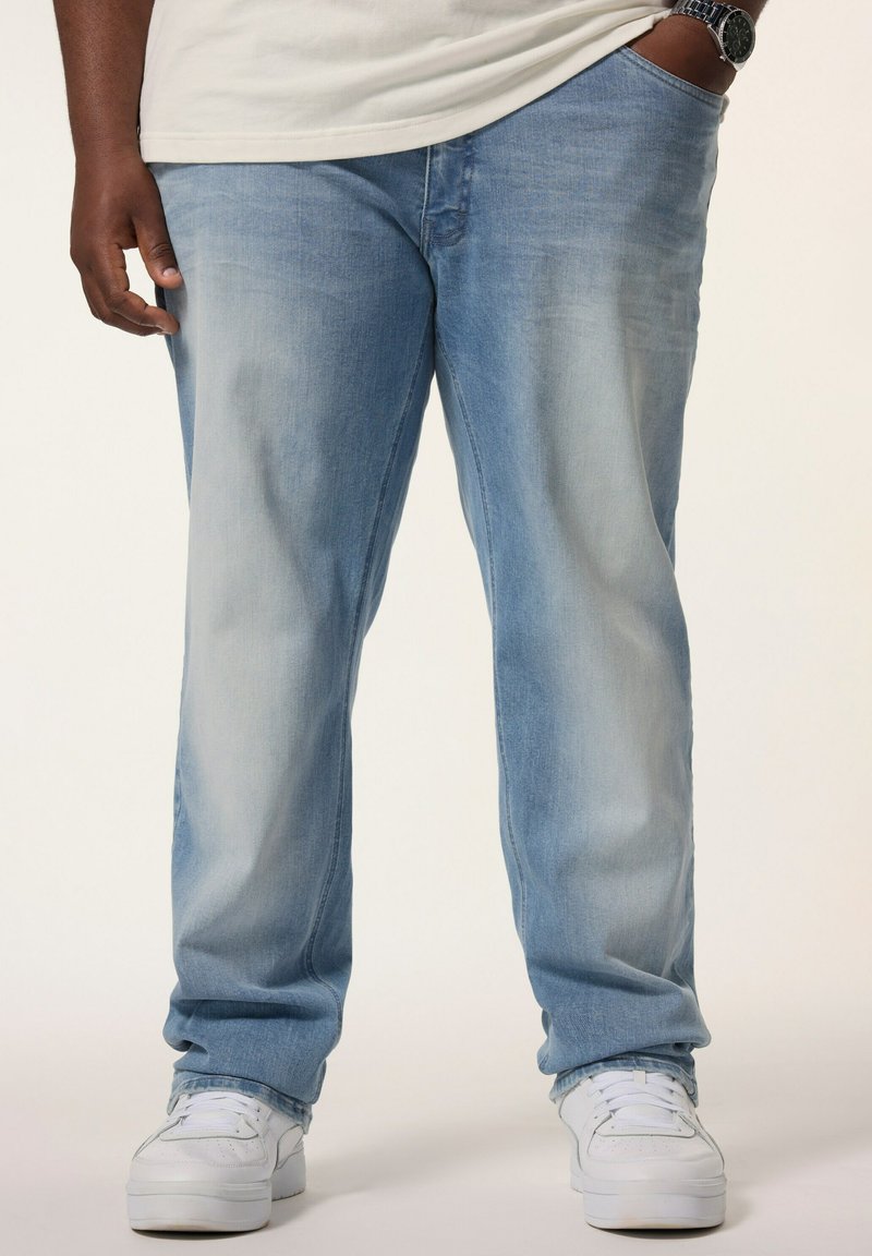Vaqueros azul claro con una textura desgastada, diseño de pierna recta y estilo de cinco bolsillos, combinados con zapatillas blancas.