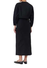 Black denim cropped jacket with long sleeves paired with a black maxi skirt featuring a subtle leopard print and back pockets.