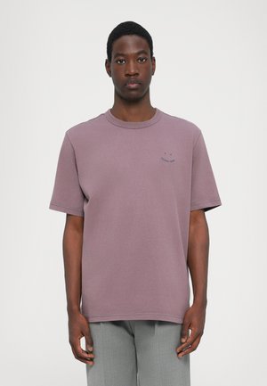 T-shirt en coton lilas avec un col rond et des manches courtes. Présente un petit design brodé en bleu marine sur la poitrine. Texture lisse.