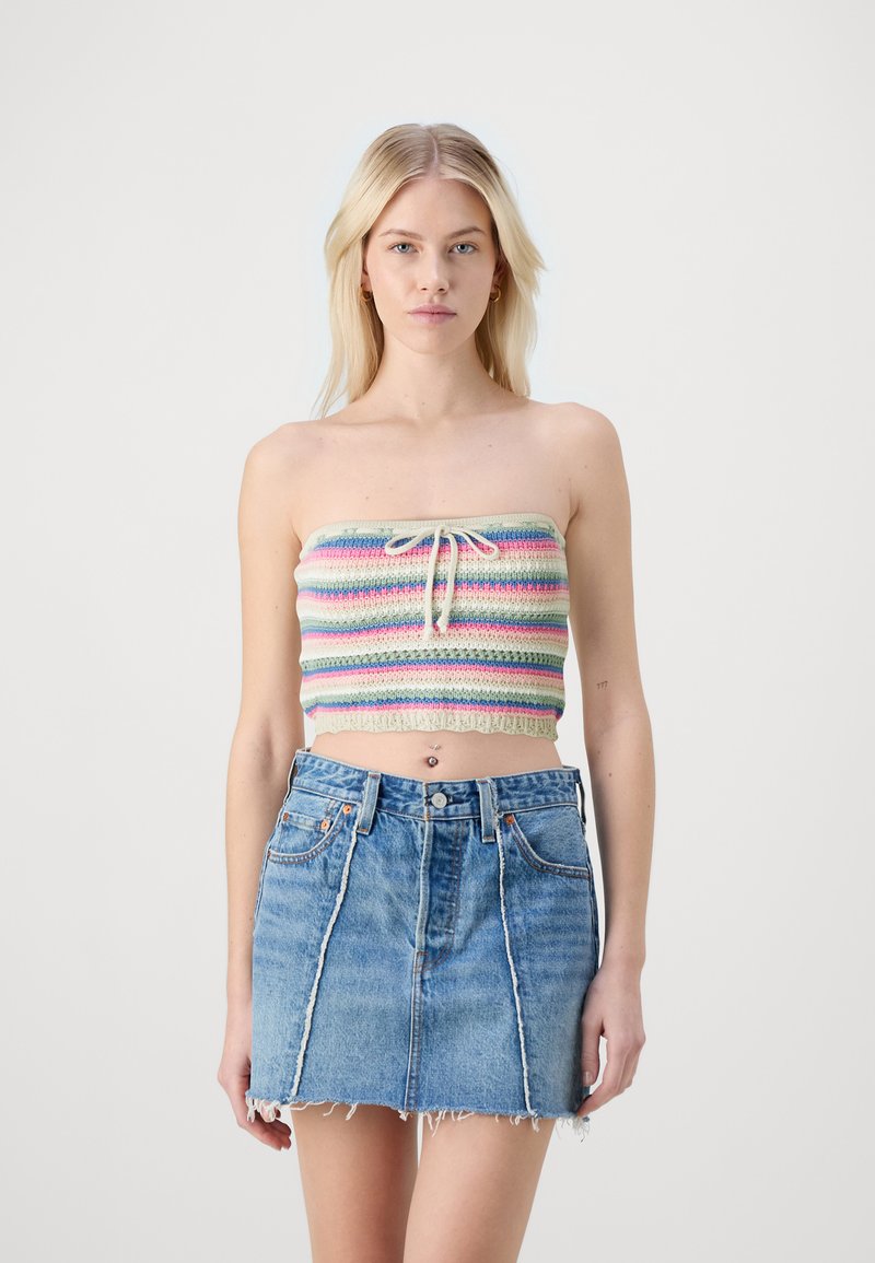 Top corto senza spalline multicolore con righe orizzontali, dotato di coulisse e rifiniture in pizzo, abbinato a una minigonna di jeans sfilacciata.