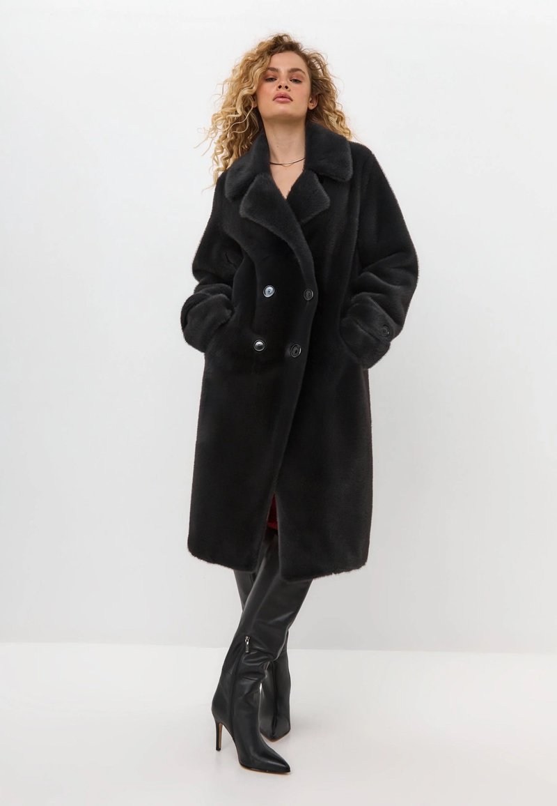 Schwarzer Kunstpelz-Doppelreiher-Mantel mit großem Kragen und Vordertaschen. Verfügt über sechs Knöpfe und eine lockere Passform, die bis zur Mitte des Oberschenkels reicht.