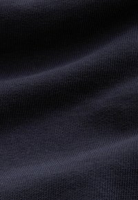 Mörk marinblått stickat tyg med synliga texturerade stygn och mjuka veck som skapar milda skuggor.