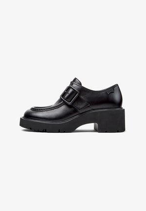 Mocassin en cuir noir à talon épais avec semelle épaisse et large bride boucle sur le dessus.
