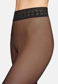 Genomskinliga bruna strumpbyxor med ett mönstrat svart elastiskt midjeband, med en slät yta och en kroppsnära passform.