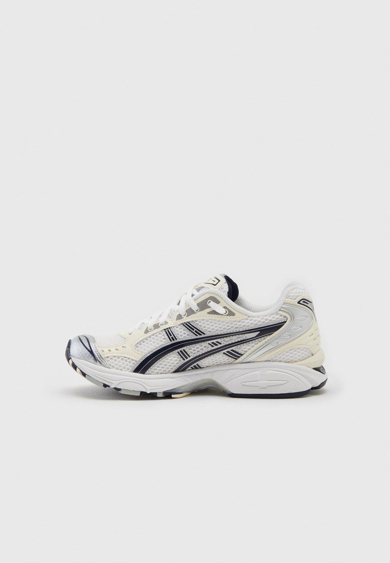 Chaussure de course athlétique blanche et noire avec dessus en mesh et semelle à motifs, vue de côté sur un fond clair uni.